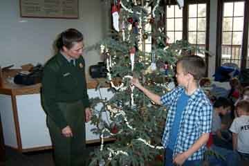 Park ranger and child decorate the tree.