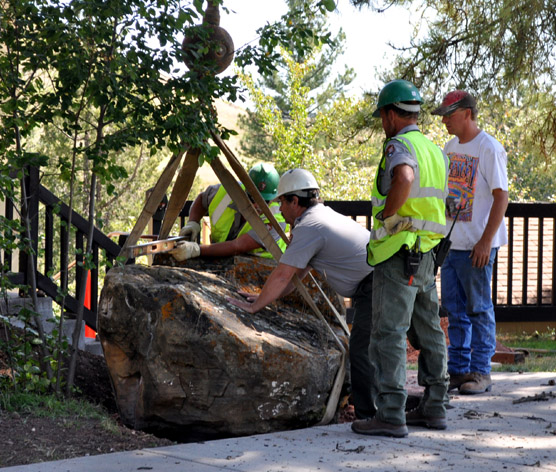 Wind Cave maintenance employees (from left) Jeff Simmons, Steve Schrempp, Mike Carder, and the JK Crane Service operator position the boulder to be used to hold the plaque. Wind Cave maintenance employees (from left) Jeff Simmons, Steve Schrempp, Mike Carder, and the JK Crane Service operator position the boulder to be used to hold the plaque.