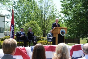 Former President Clinton speaks at the dedication ceremony for the Clinton Birthplace Home. The two-story, white frame house is in the background.
