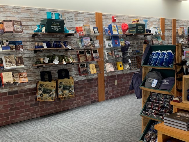 Bookstore and giftshop with Civil War themed items and books on shelves along the wall and displays on island display with hanging items from slat-wall shelves