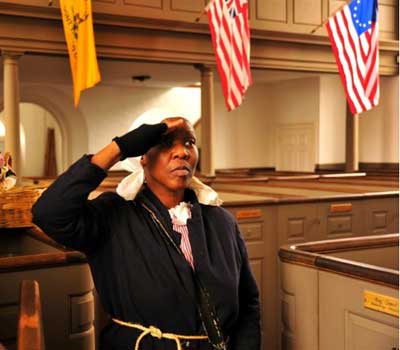 Carolyn Evans as Harriet Tubman saluting in a church