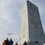 visitor at 60 ft. granite monument watching four military planes.