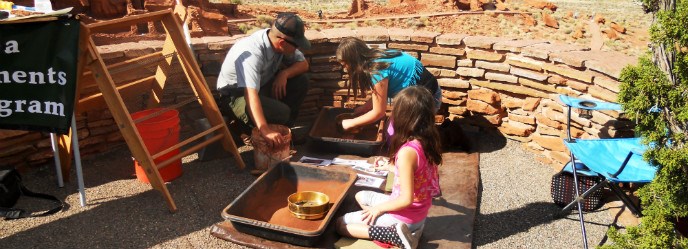 Two girls sifting artifacts with a park archeologist