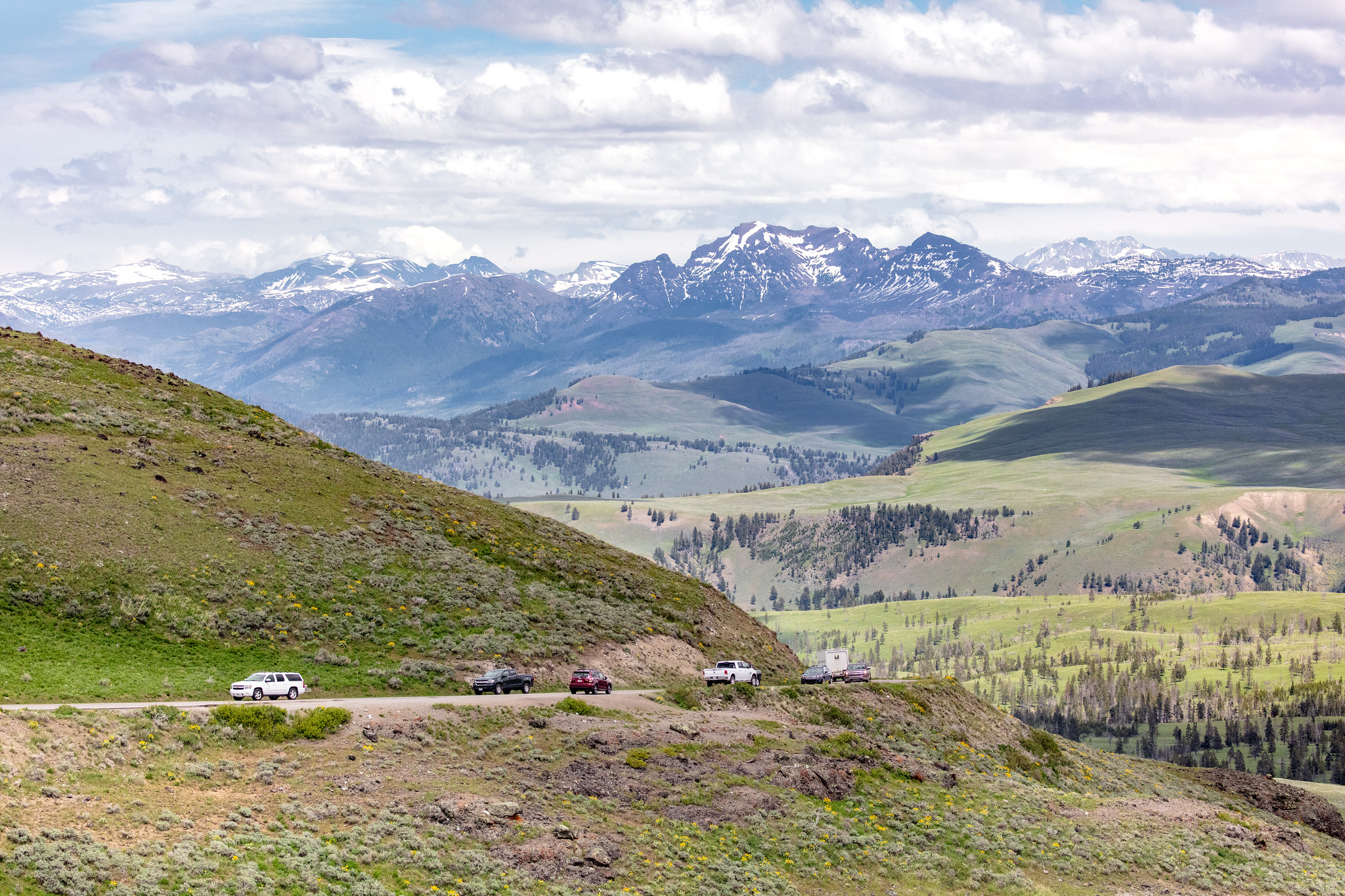 Cars driving on Dunraven Pass with mountains in background