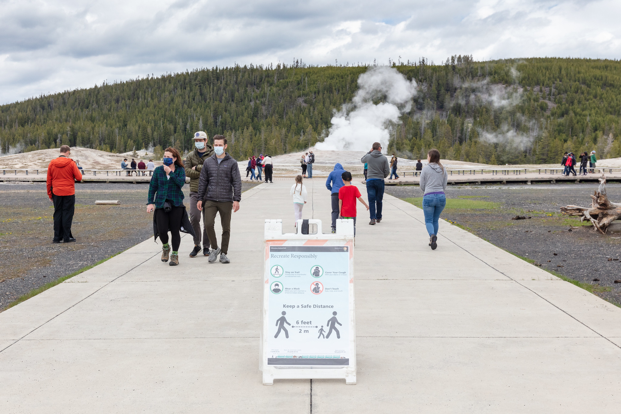 Visitors wearing masks and social distancing in front of Old Faithful Geyser