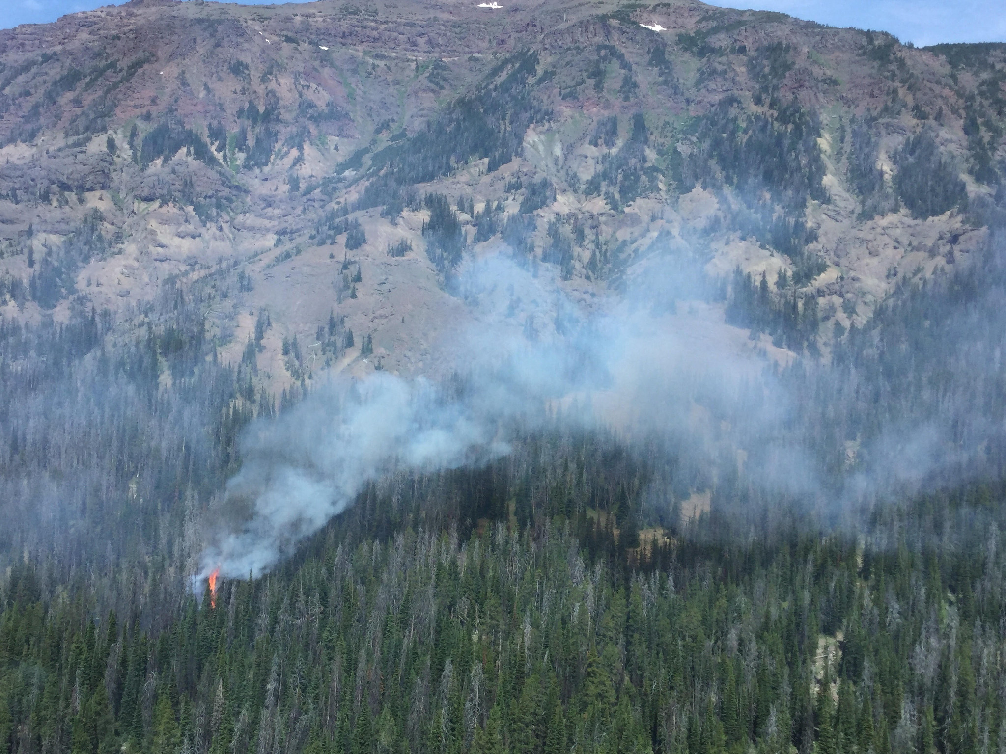 flames from a small wildfire in mountainous terrain