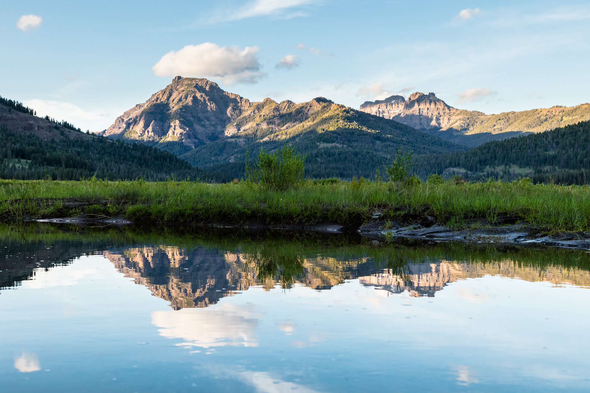 Mountains are reflected in the still waters of Soda Butte Creek at sunset
