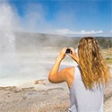 Person photographing an erupting geyser