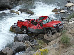 Car wrecked in accident turned upright by the bank of the river.