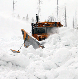 A snowplow plunges through a huge snowbank.