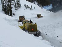 Snowplows plow through deep snow.