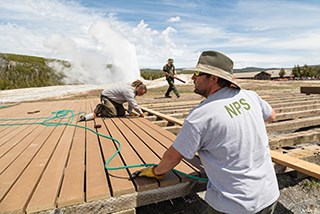 A man lays lumber in place to build a boardwalk