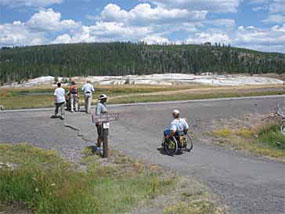 A visitor in a wheelchair visits the Old Faithful area.