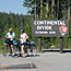 Two bikers pause in front of the Continental Divide sign.