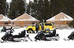 Snomobiles line up in a parking lot at Old Faithful during winter