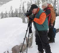 A photographer photographs the snowy landscape at Gibbon Canyon Overlook.