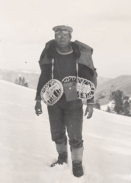 Dr. James E Church standing on snow with snowshoes draped over his neck.