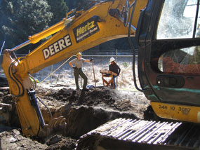 Two people monitor construction hoe at work