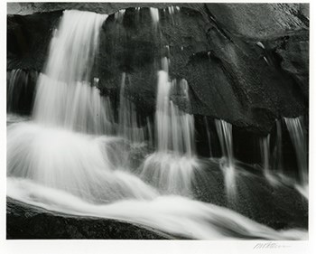 Photo of water cascading over rocks in black and white.