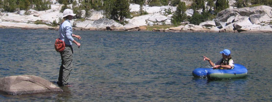 Two scientists hold nets while immersed in an alpine lake