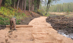 Worker unrolls blanket onto soil to prevent soil from washing away