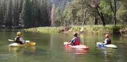 Three kayakers float down the Merced River's calm waters.