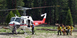 SAR team members carrying a patient to a waiting helicopter