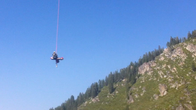 Ranger dangles from a helicopter (not seen) while short-hauling a patient.