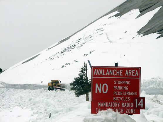 Snow plow in snow with avalanche zone sign