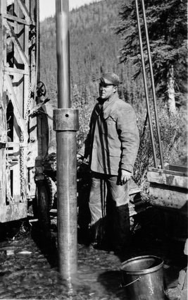 A drill crew worker using the new "Prospector" drill rig to test Coal Creek, 1935.