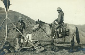 Historic photo of two surveyors, one on horseback, working on the international boundary project.