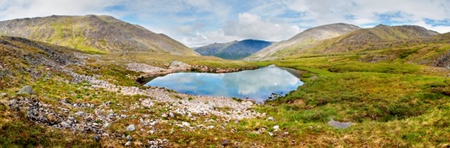 A panoramic photo of an alpine lake in a valley