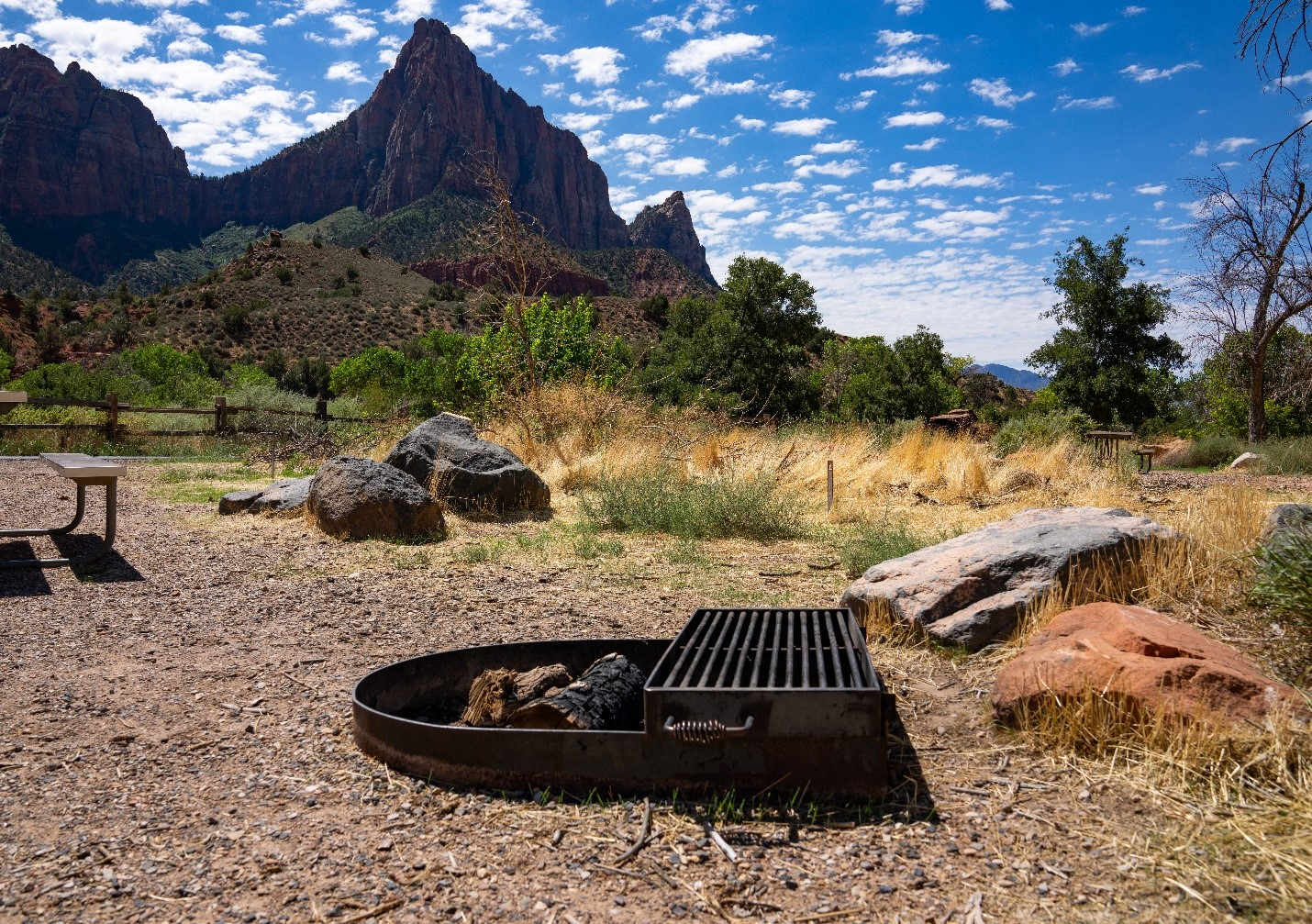 A fire pit in a campground with sandstone in the background