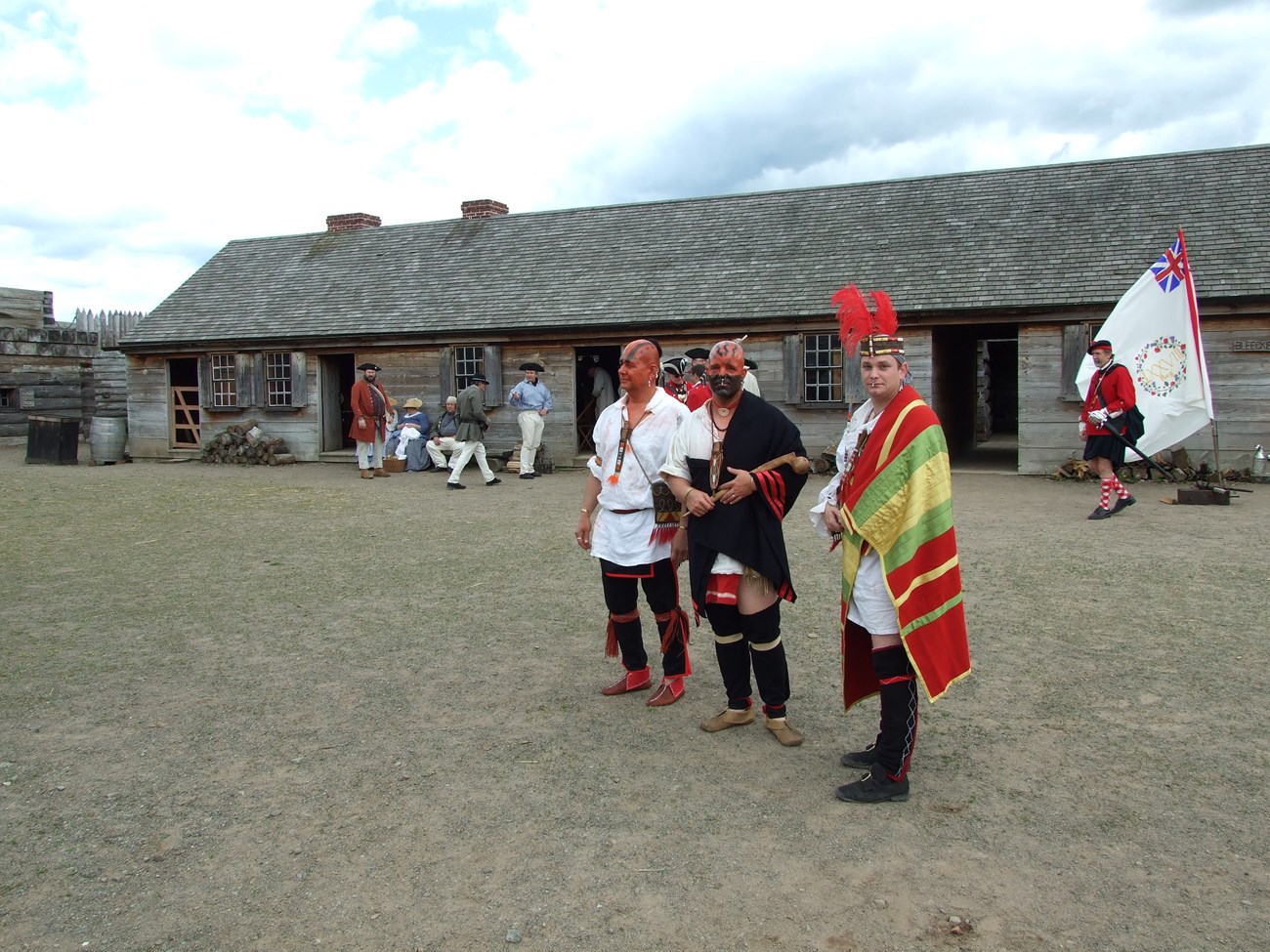 Three men in elaborate outfits with feathers and paints adorning their heads.