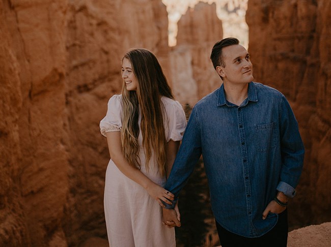 A man and woman stand at the top of a trail of winding switchbacks.