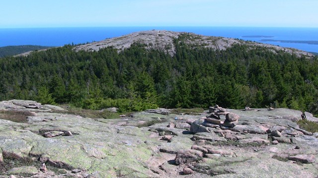 blue sky beyond rocky mountain top and trees