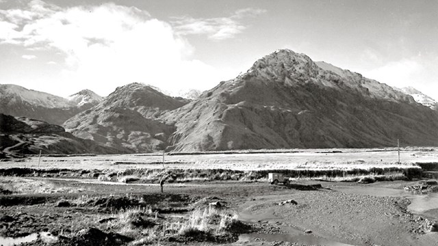 Black and white landscape photo of mountains and water. 