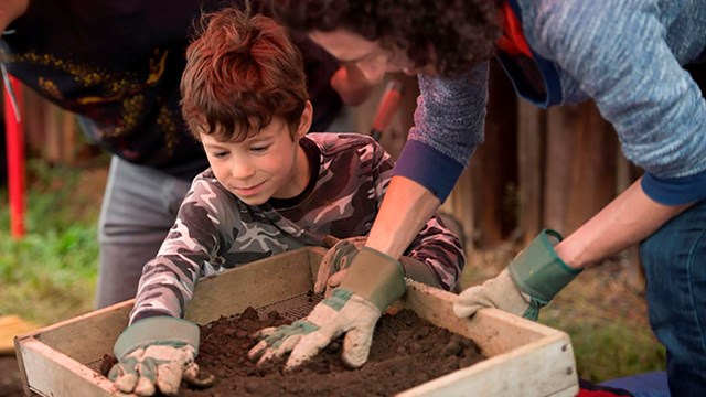 Boy and woman screening dirt.