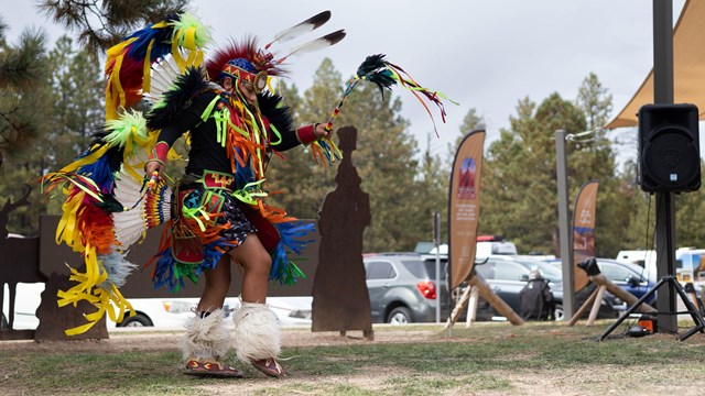 A Native American dancer in traditional clothing does a Fancy Dance.