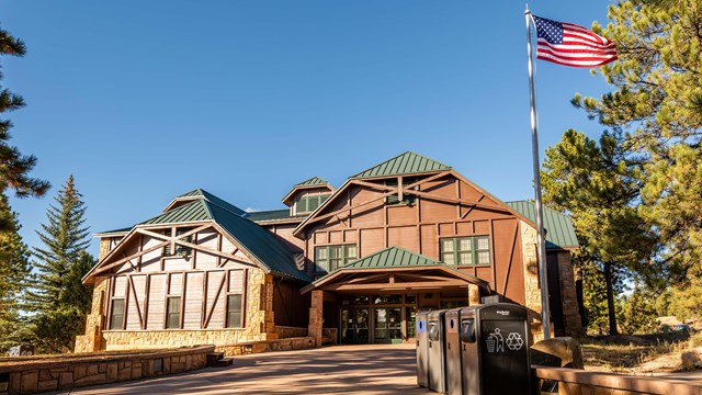 A brown wooden building with a flag pole out front flying an American flag.