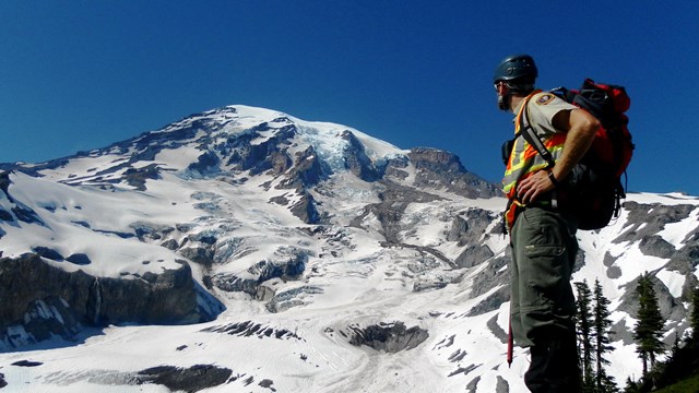 park ranger with glaciated peak in background