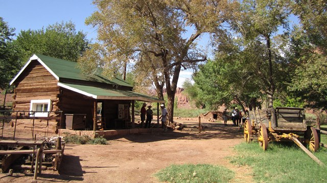 A wagon sits next to a historic log ranch house