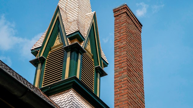 A church steeple, painted in green and yellow, along with a brick chimney.