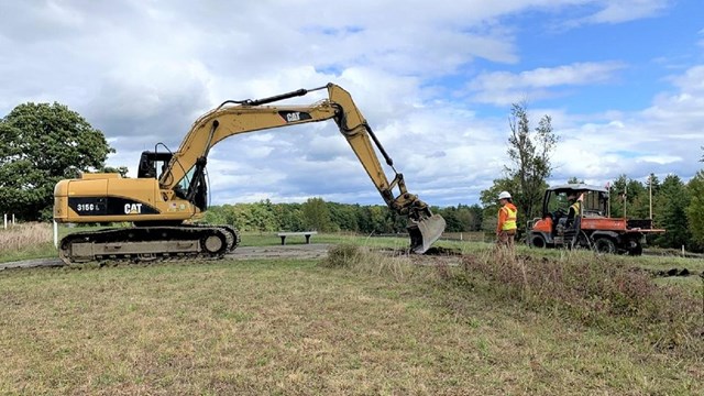 A couple of construction crew members working with an excavator 