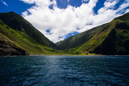 a wide and green valley with sky above and water below