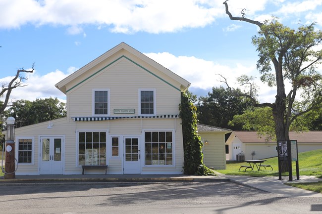 An off-white historic store under a blue sky. A wheelchair ramp is visible at the right.