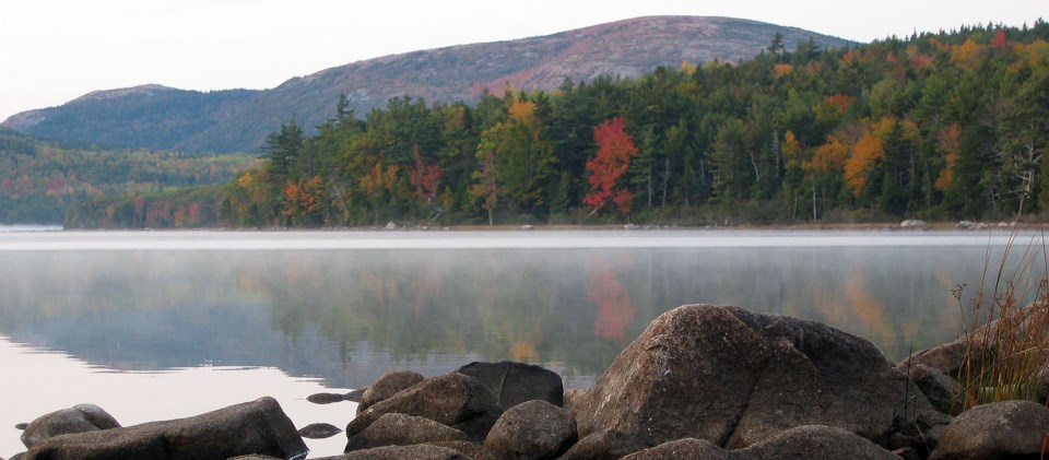 Colorful trees reflected in lake with mountains in background