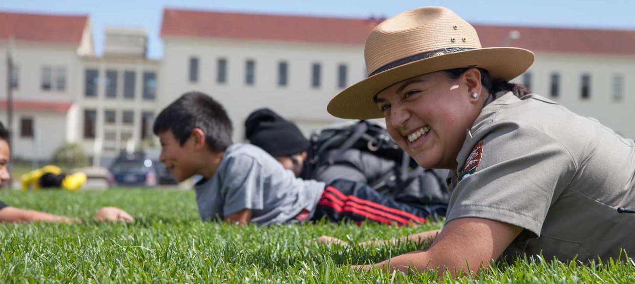 ranger on grass with children and fort behind