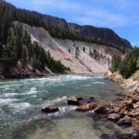 A river flows through a canyon with pale, sloping walls.