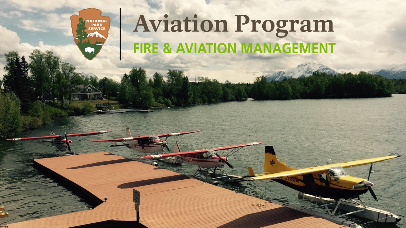 Several floatplanes sit fixed to a dock on the water.